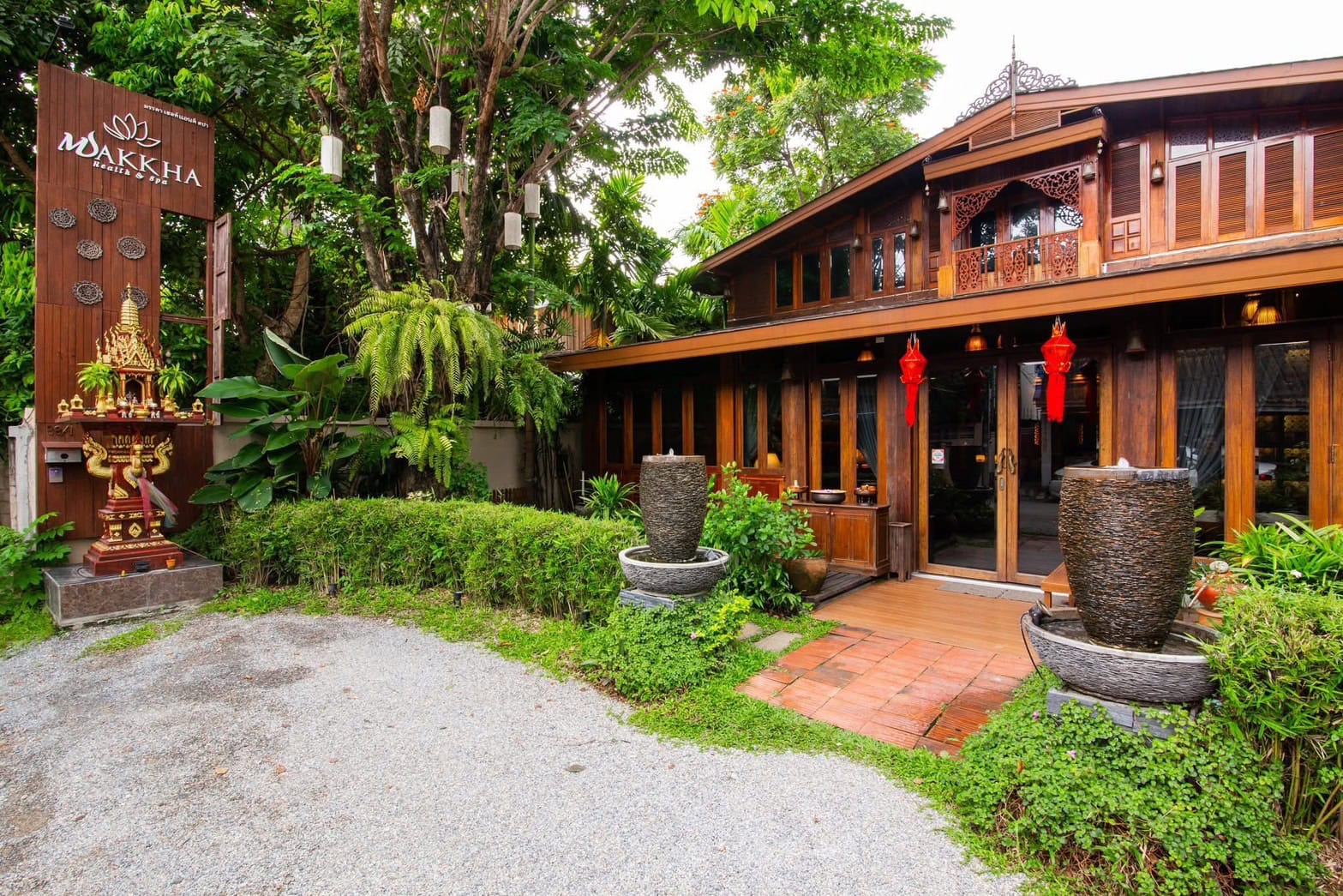 Thai-style wooden spa building surrounded by lush greenery and traditional decor at Makkha Spa in Chiang Mai.