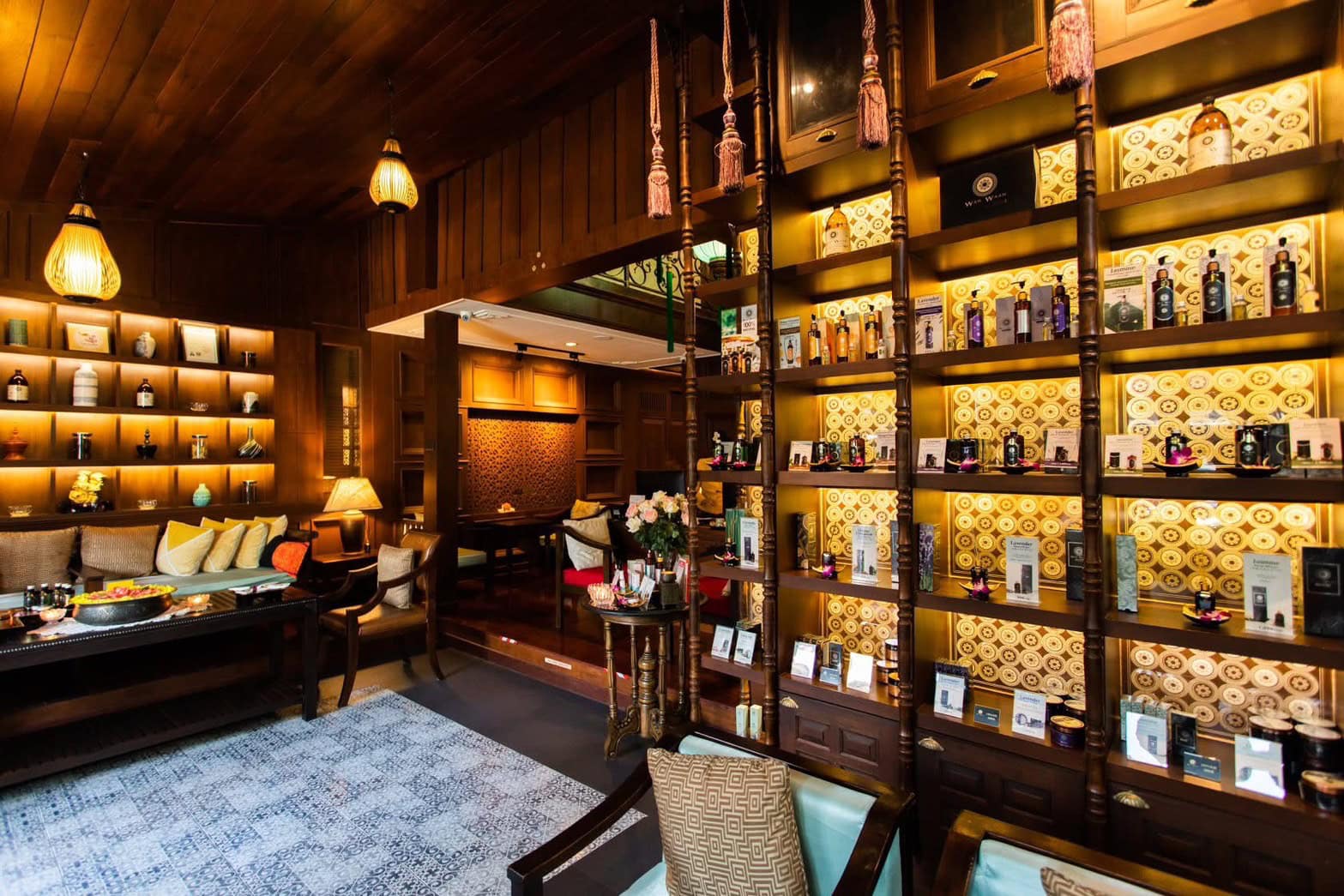 Luxurious spa interior with warm wood tones, elegant shelving with skincare products, cozy seating area, and ambient lighting in Chiang Mai, Thailand.