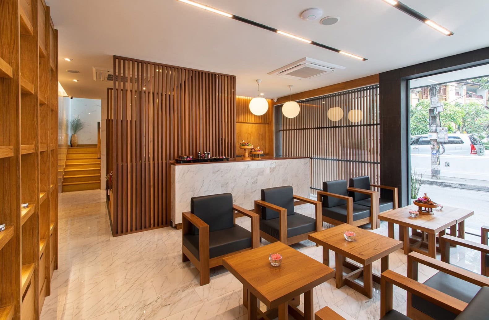 Relaxing spa lounge area with modern wooden decor, black leather seats, and soft lighting at Makkha Health & Spa in Chiang Mai.