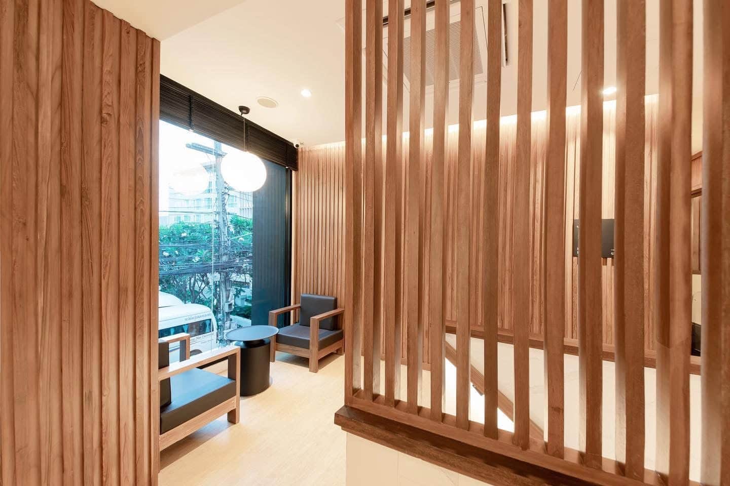 Cozy corner inside Makkha Health & Spa in Chiang Mai with wooden decor, modern chairs, large window, and ambient lighting, creating a relaxing atmosphere for visitors.