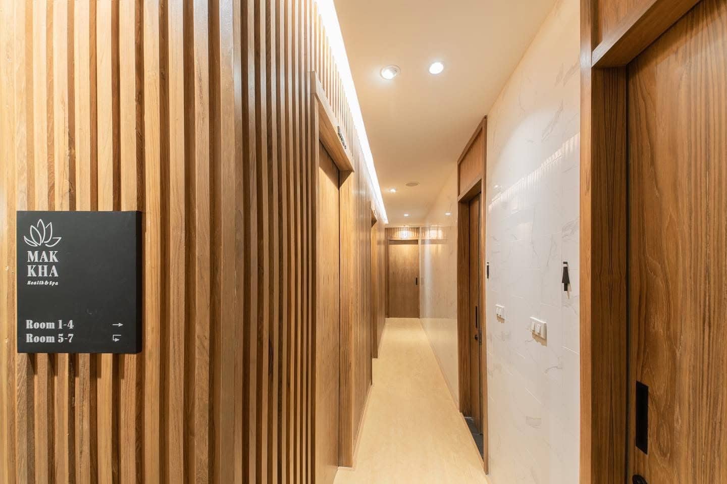 Luxurious wooden corridor inside Makkha Health & Spa in Chiang Mai, featuring elegant sliding doors and calming warm lighting.