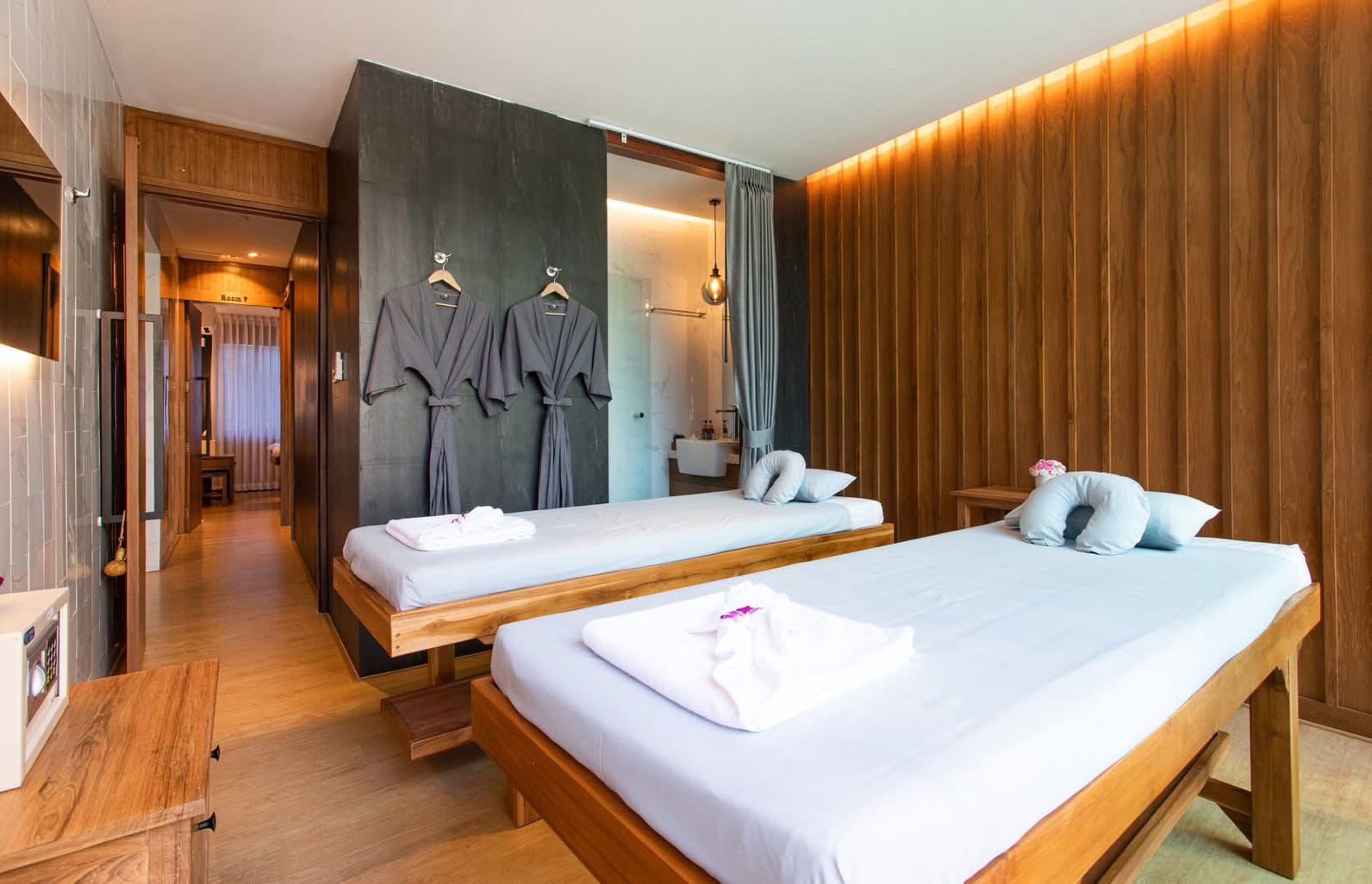 Comfortable Thai massage room with two single beds, wooden furnishings, and relaxing ambiance at Makkha Health & Spa, the best spa in Chiang Mai.
