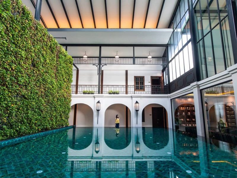 Luxurious indoor swimming pool at Makkha Health & Spa Chiang Mai, with lush greenery wall, natural lighting, elegant architecture, perfect for relaxation and wellness.