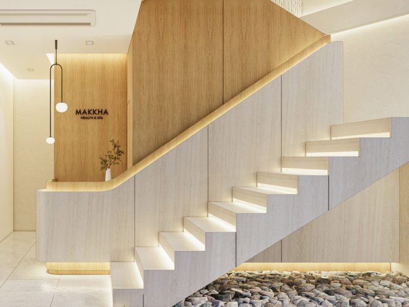Relaxing spa reception area with modern wooden staircase, soft lighting, and minimalist decor at Makkha Spa in Chiangmai, emphasizing tranquility and luxury.