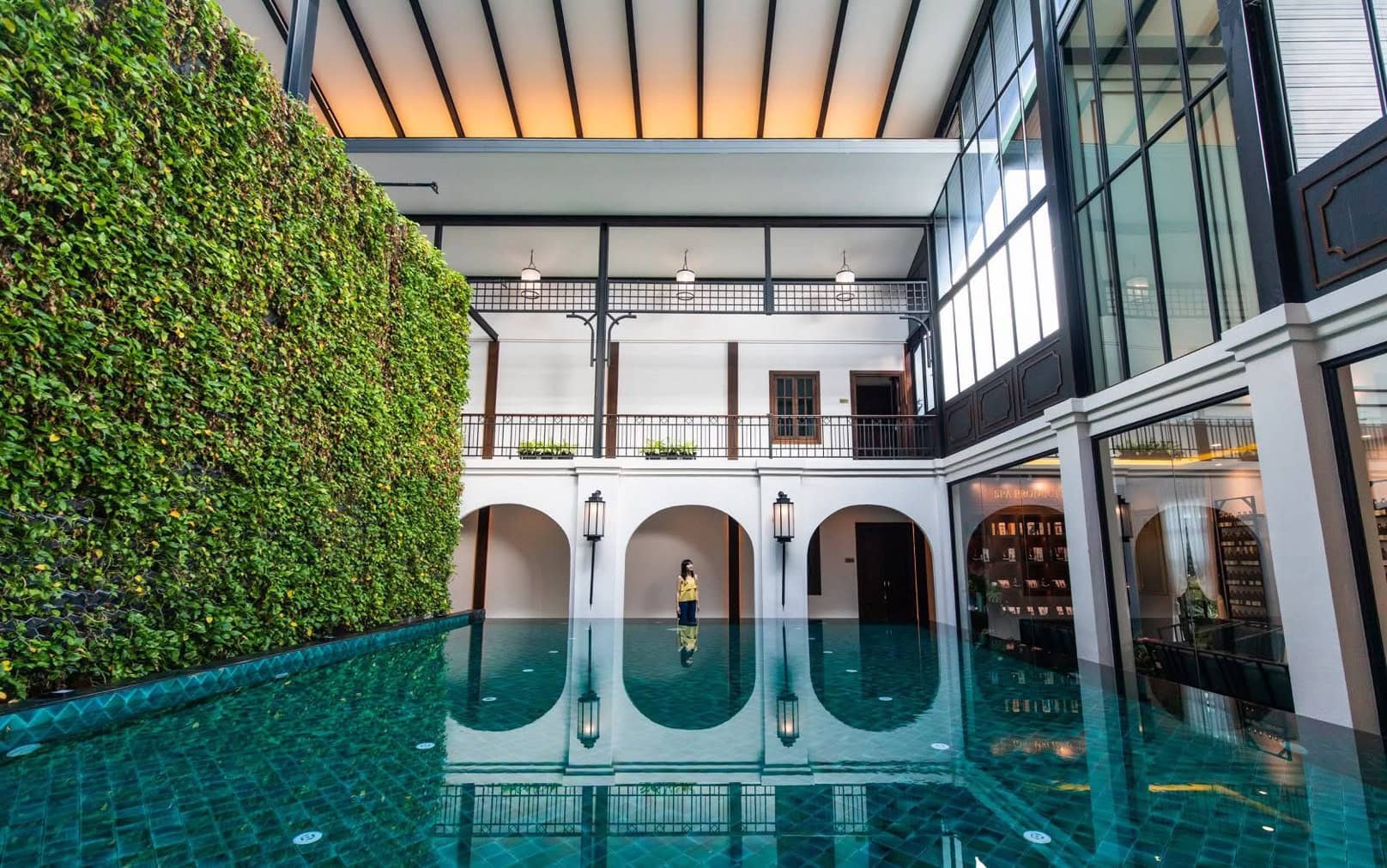 Luxurious indoor swimming pool at Makkha Health & Spa Chiang Mai, with lush greenery wall, natural lighting, elegant architecture, perfect for relaxation and wellness.
