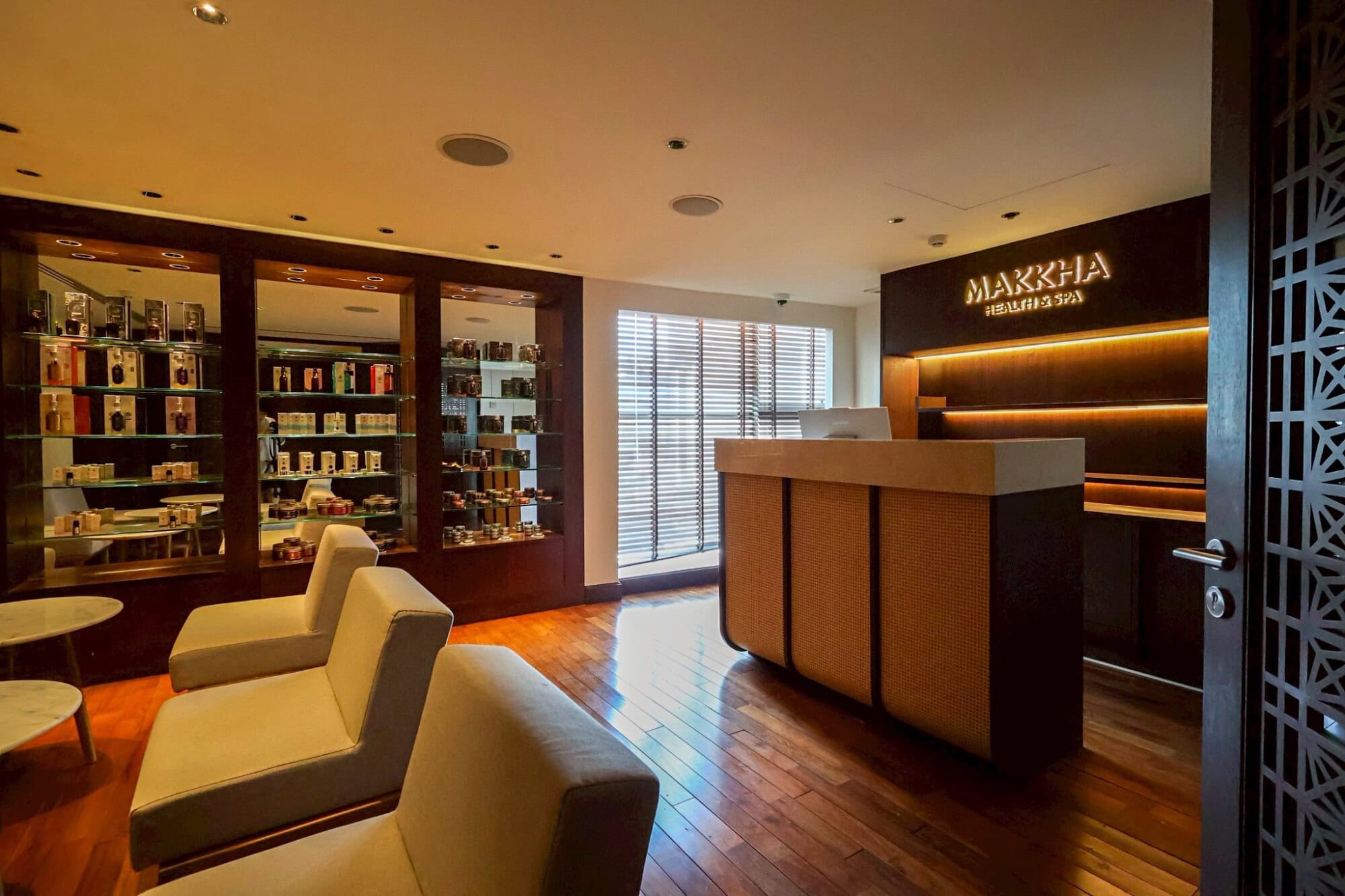 Luxurious Chiang Mai spa reception area with warm lighting, comfortable seating, and an elegant display of skincare products, offering the best relaxation experiences at Makkha Spa.